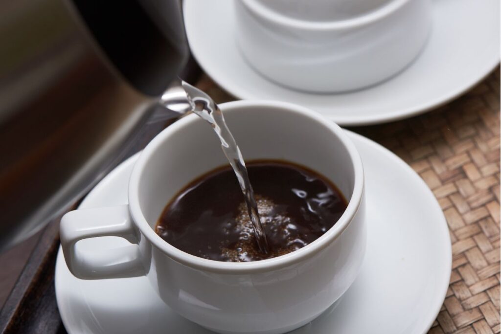 Pouring hot water over instant coffee in a cup